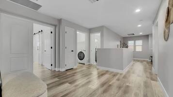 A spacious, modern interior with a central island, wooden flooring, and white walls.