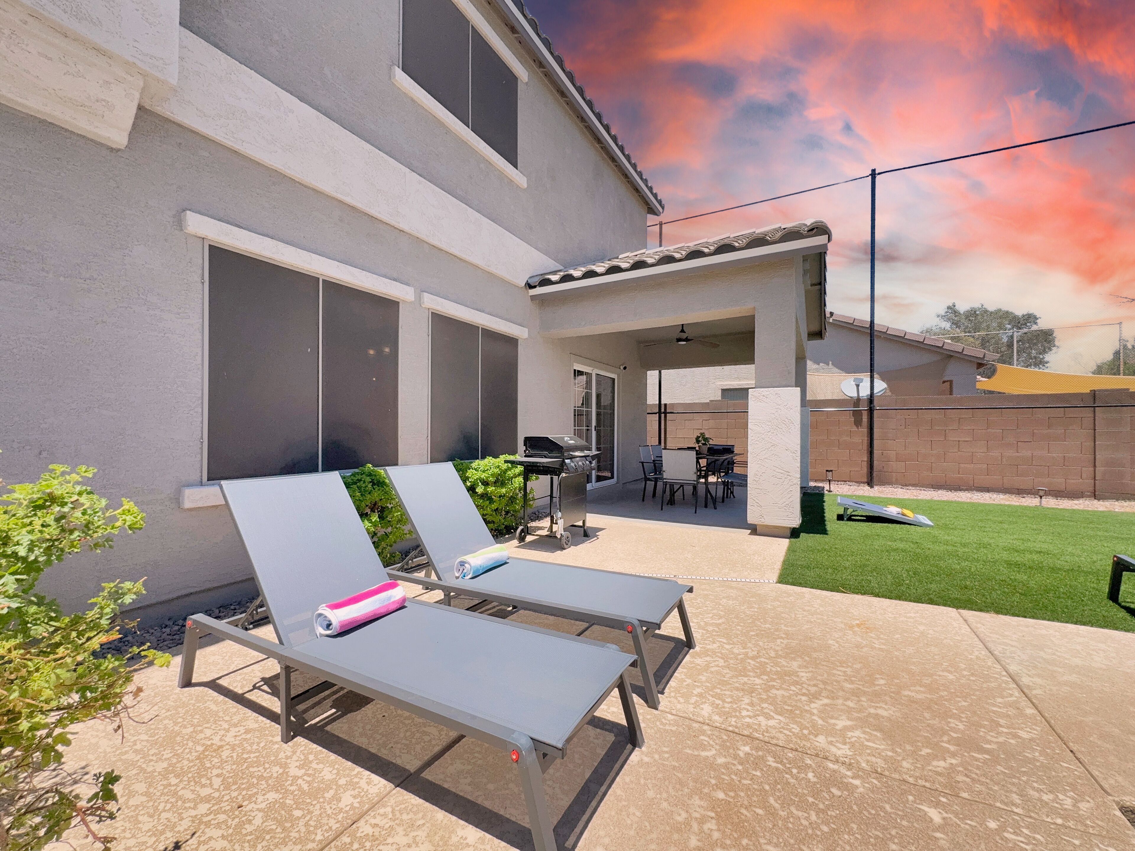 A patio with two lounge chairs, a barbecue grill, and a covered seating area.