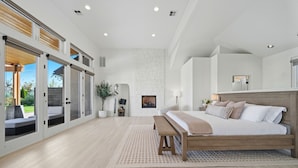 A spacious bedroom with a large bed, a bench, and a view of the outdoors through sliding glass doors.