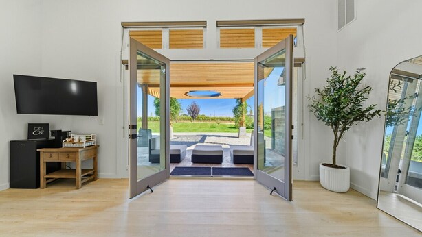 A modern living room with a large sliding glass door leading to an outdoor patio.