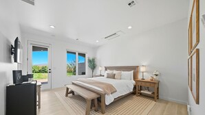 Une chambre à coucher moderne avec un grand lit, des tables de chevet, un bureau et un téléviseur.