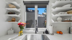 Eine moderne Küche mit weißen Schränken, einer Edelstahl-Spüle und einem Fenster mit Blick auf Gebäude.