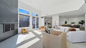 Ein modernes Wohnzimmer mit einer Couch, Sesseln und einem Couchtisch. Im Hintergrund ist eine Küchenzeile erkennbar.