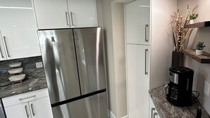 Una cocina moderna con electrodomésticos de acero inoxidable, armarios blancos y encimera de mármol.