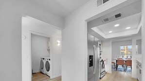 Una cocina moderna con refrigerador, comedor y vistas al exterior.