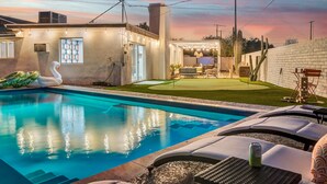 Ein Swimmingpool mit Liegestühlen, einer Schwaneinrichtung und einer Terrasse mit Lichterketten.
