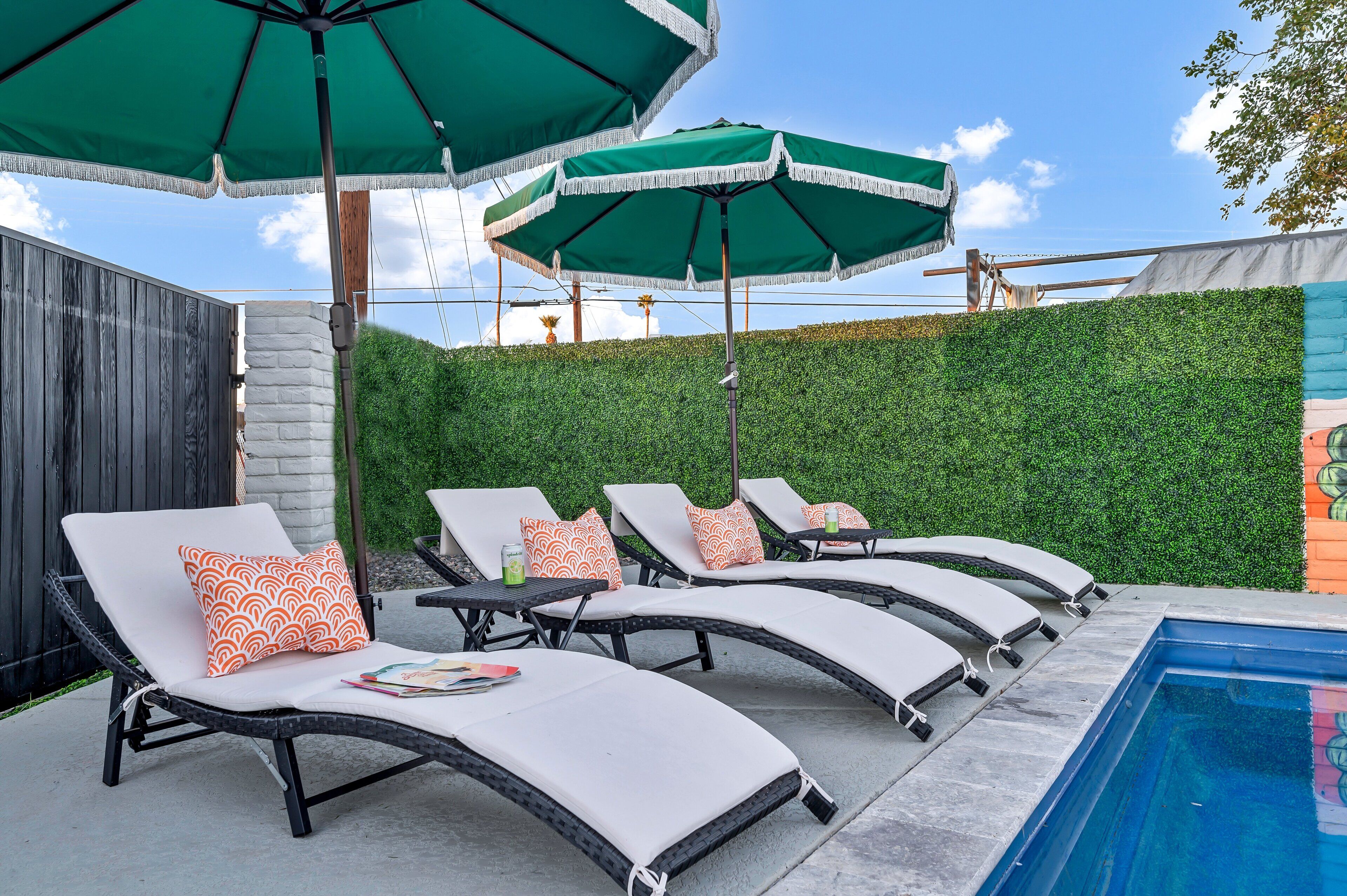 A poolside area with lounge chairs and green umbrellas.