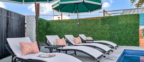 A poolside area with lounge chairs and green umbrellas.