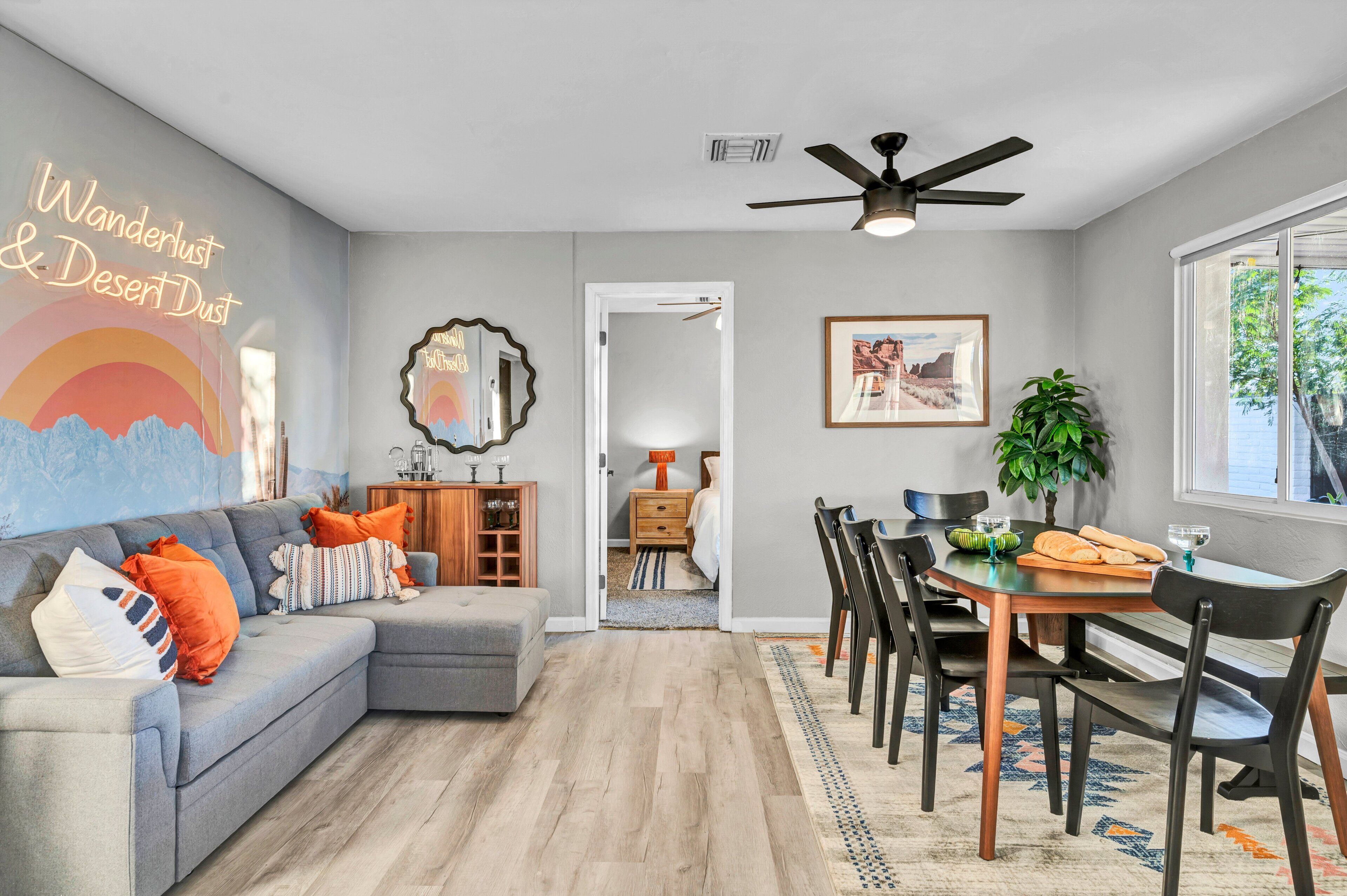 Un salon moderne avec un canapé gris, une table à manger en bois et un ventilateur de plafond.