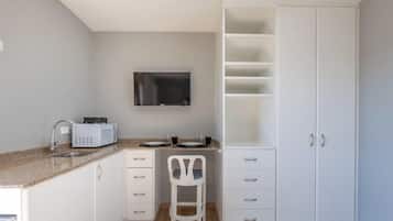 A compact kitchen with a microwave, sink, and white cabinets.