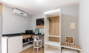A compact kitchenette with a microwave, coffee maker, and a small dining area with a chair and a table. - Studios at Upper Residence - UPP (Curitiba)
