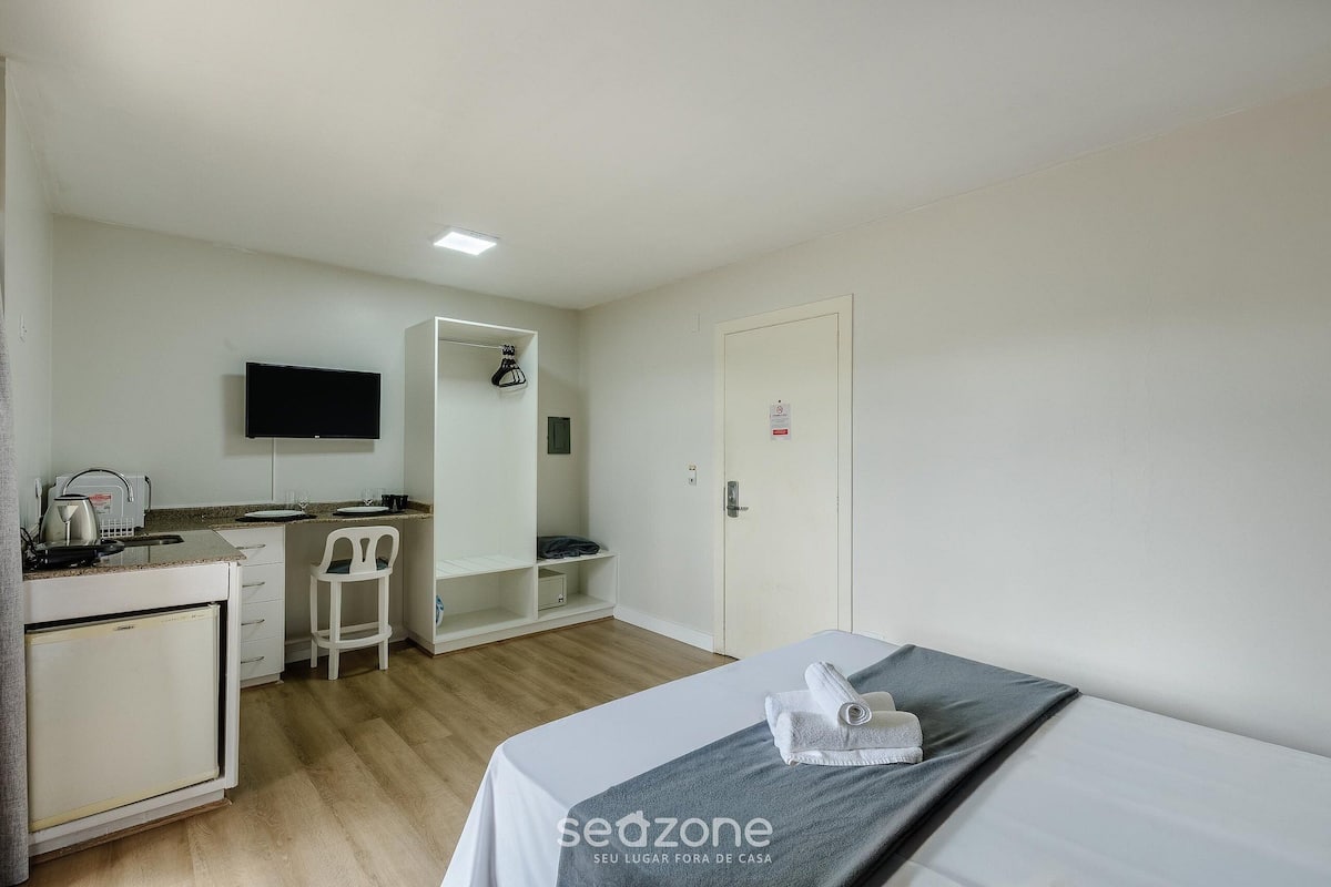 Een compacte hotelkamer met een bed, een kleine kitchenette, een televisie en een kledingkast.