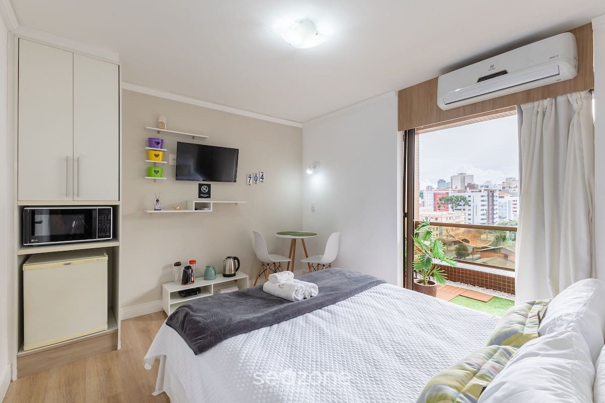 Hotelkamer met een bed, bureau, televisie, magnetron, minibar en balkon met uitzicht op de stad.