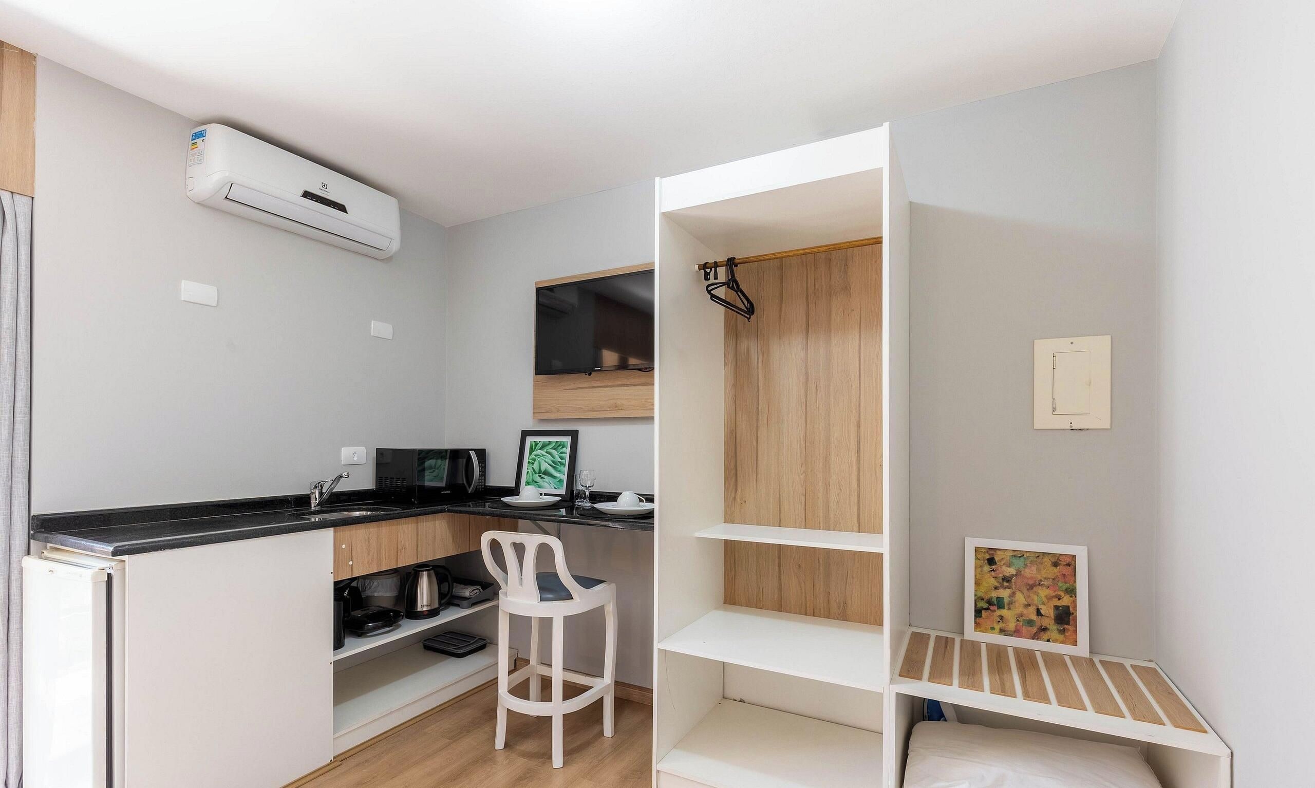 A compact kitchenette with a microwave, coffee maker, and a small dining area with a chair and a table.