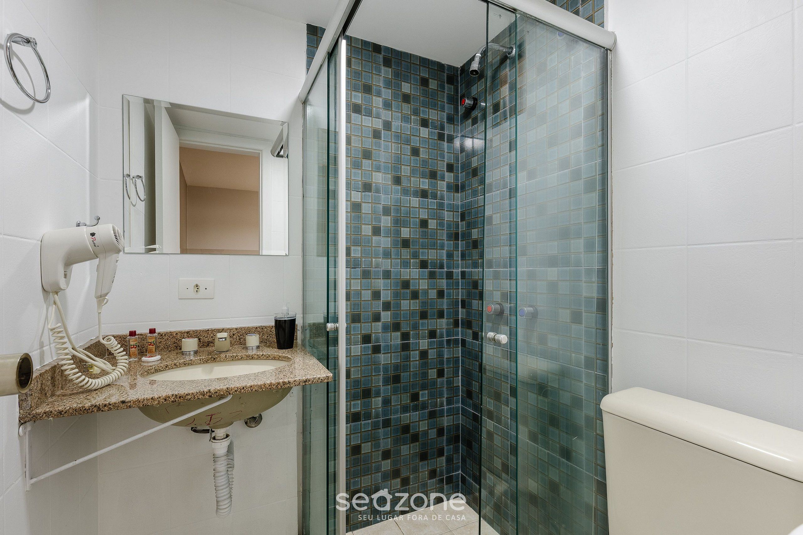 A bathroom with a glass shower enclosure, a sink with a towel rack, and a mirror.