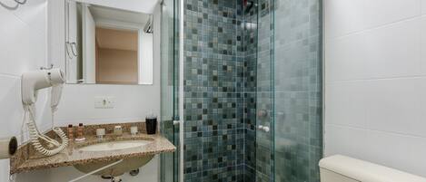 A bathroom with a glass shower enclosure, a sink with a towel rack, and a mirror.