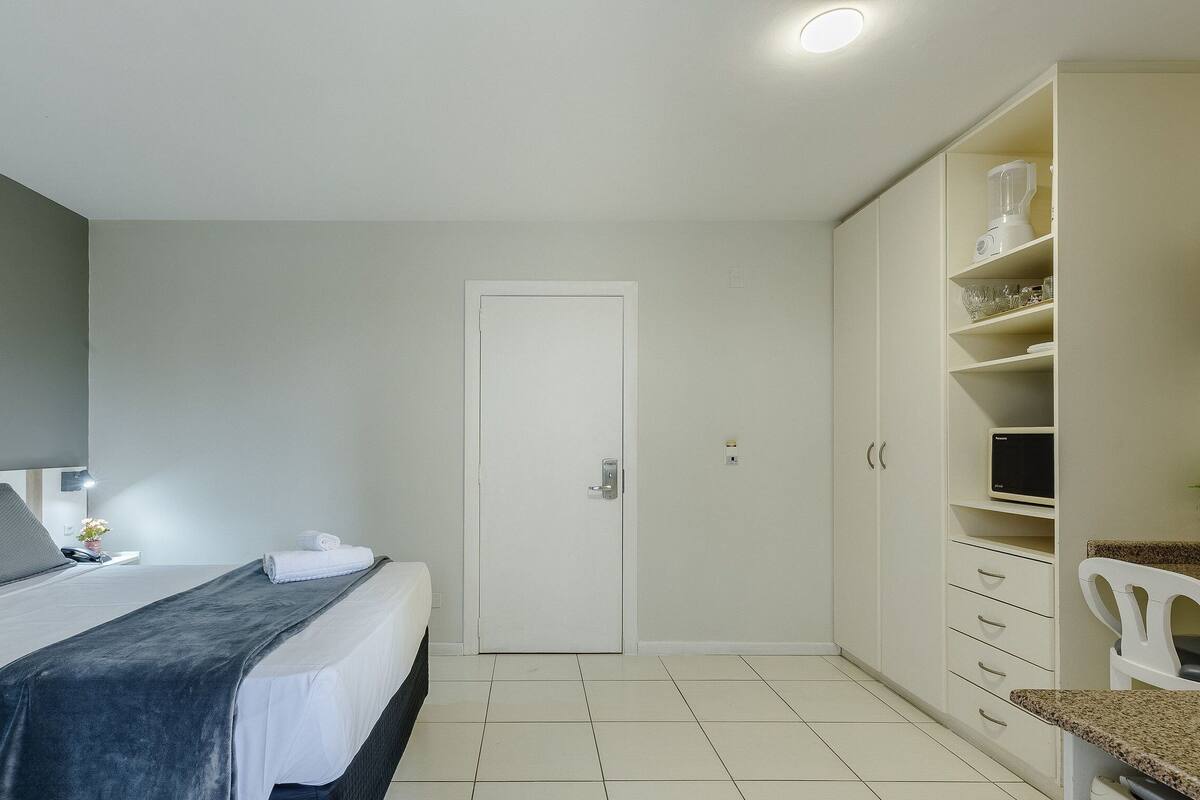Een slaapkamer met een bed, een kledingkast, een bureau en een stoel.