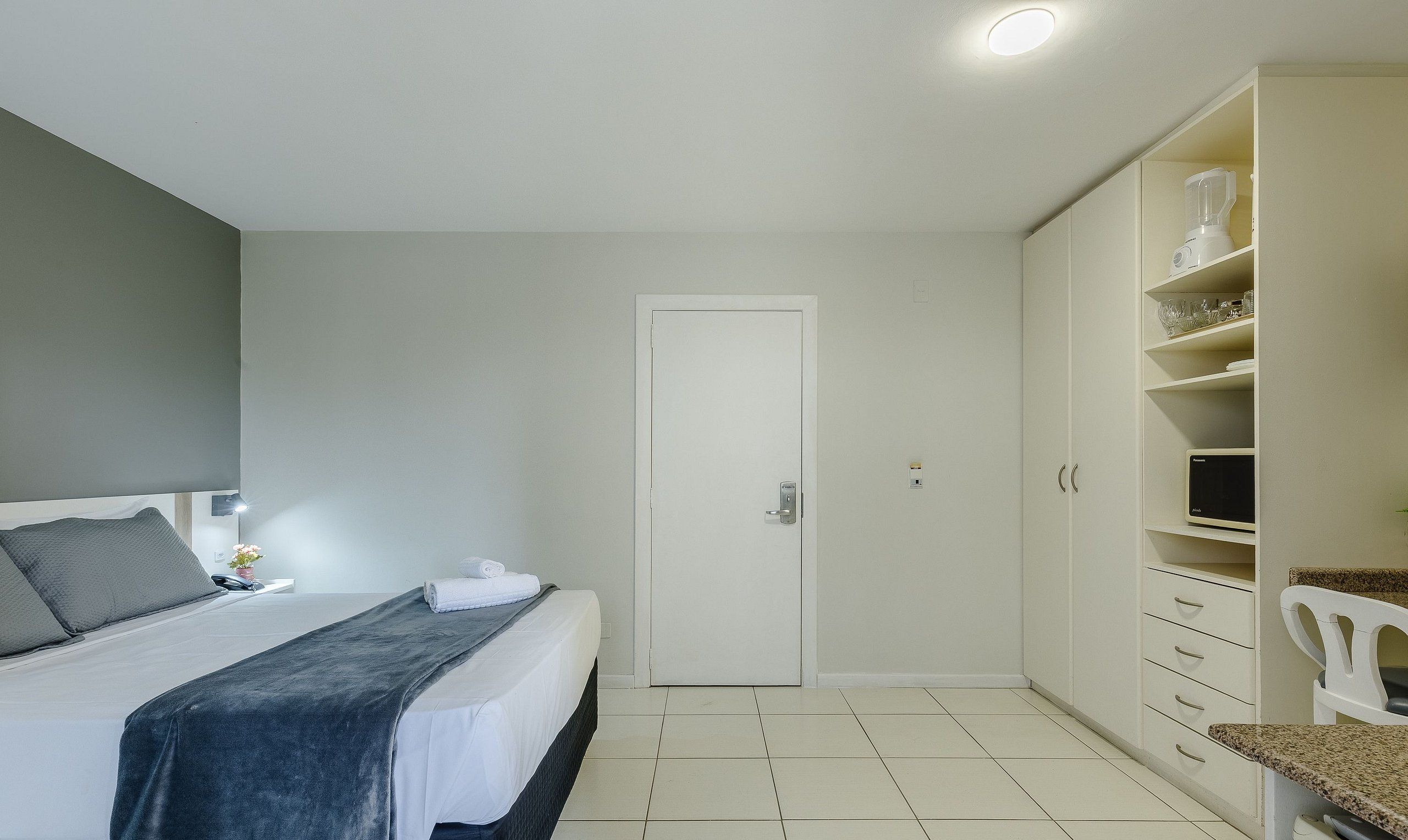 A bedroom with a bed, a wardrobe, a desk, and a chair.
