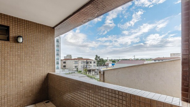A balcony with a tiled wall, a view of buildings, and a clear sky. - Studios at Upper Residence - UPP (Curitiba)