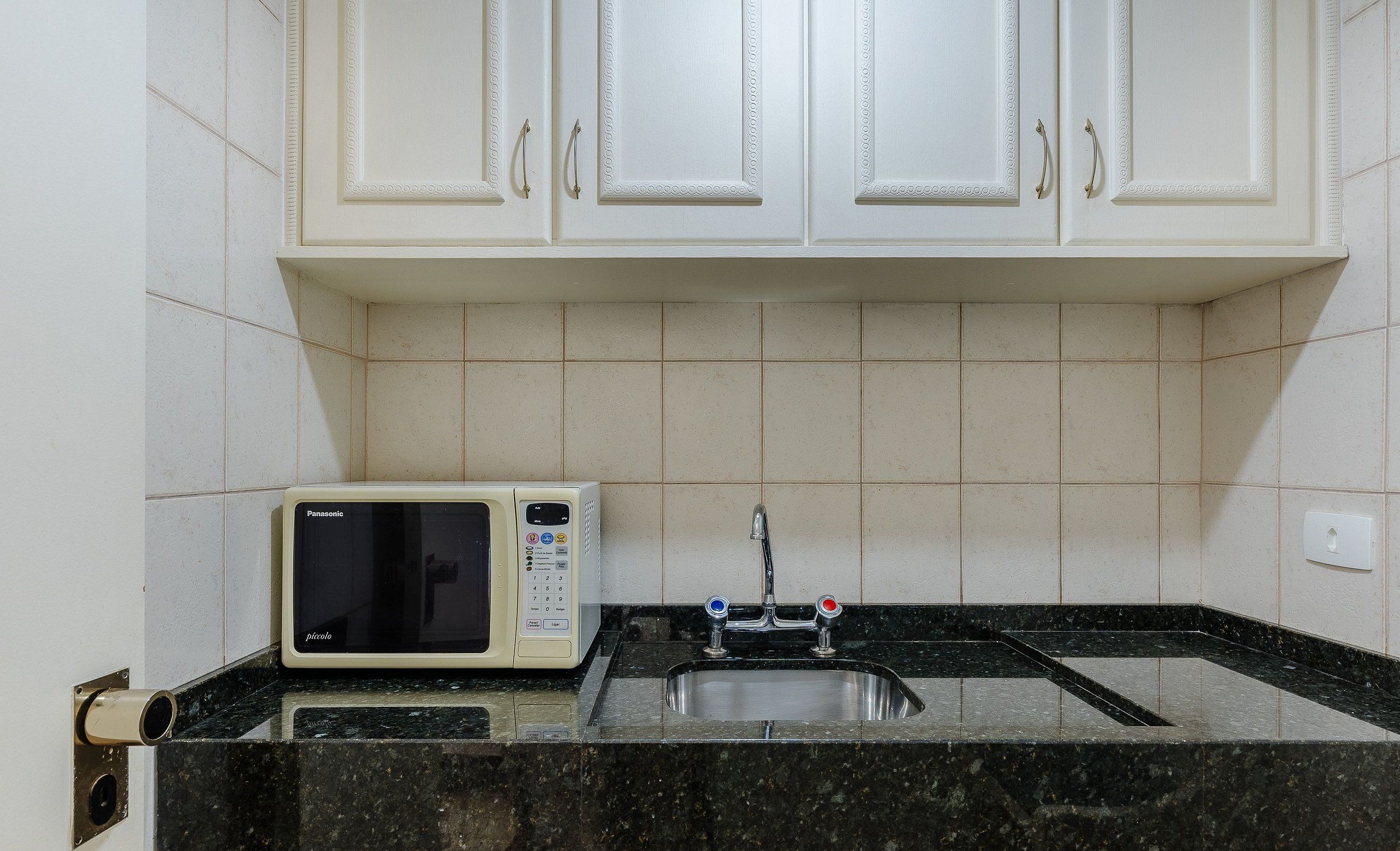 A kitchen with white cabinets, a microwave, and a sink.