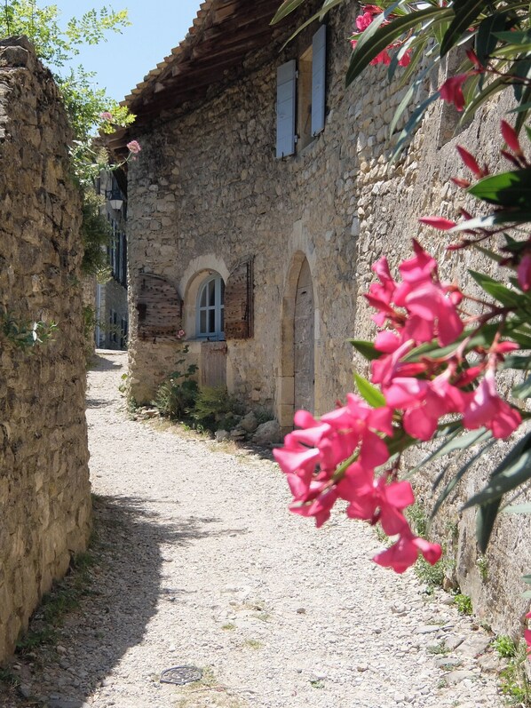 A narrow stone pathway leading to a rustic stone building with arched windows and a small door.