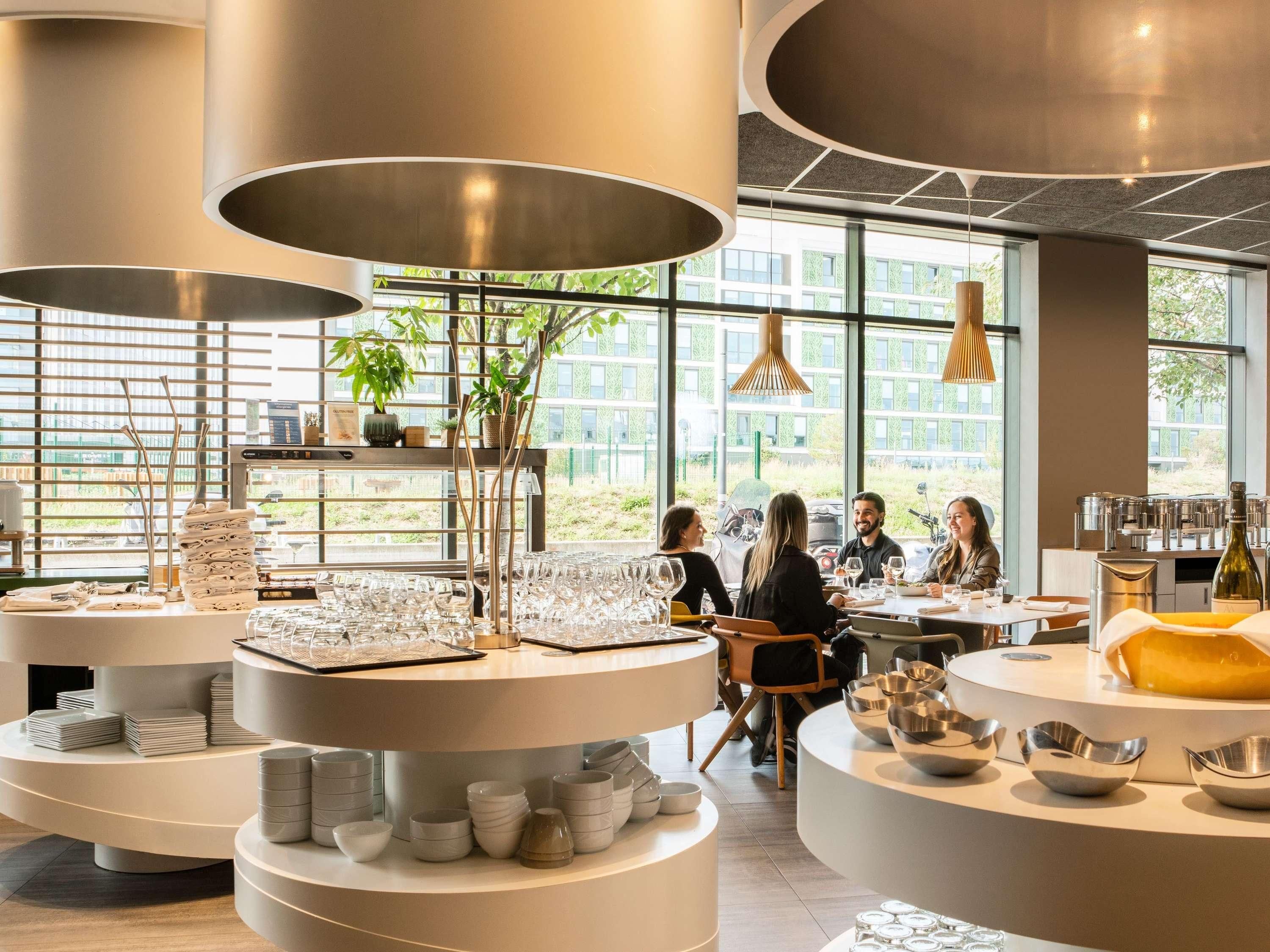 A modern interior with round tables, glassware, and plants.