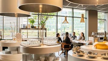 A modern interior with round tables, glassware, and plants.