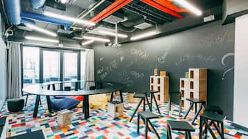 Un espacio de oficina moderno con una mesa redonda, taburetes negros y un piso con un patrón geométrico de colores.