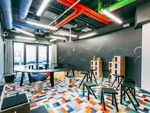 Un espacio de oficina moderno con una mesa redonda, taburetes negros y un piso con un patrón geométrico de colores.