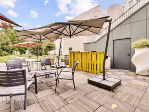 Un patio al aire libre con mesas y sillas, una valla amarilla y una maceta grande.