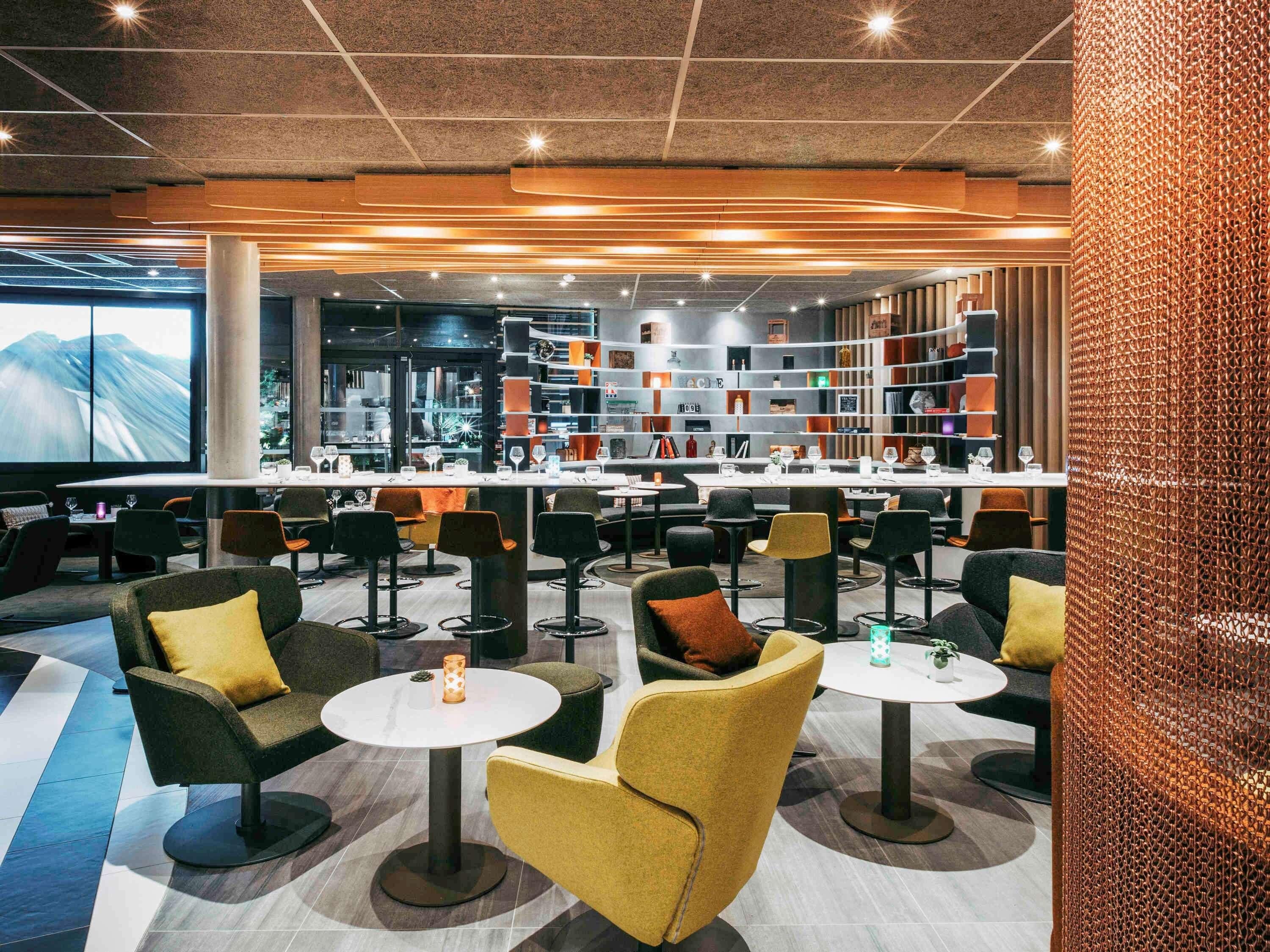Un moderno espacio lounge con asientos, mesas y una zona de bar con estanterías.