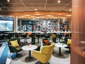 Un moderno espacio lounge con asientos, mesas y una zona de bar con estanterías.