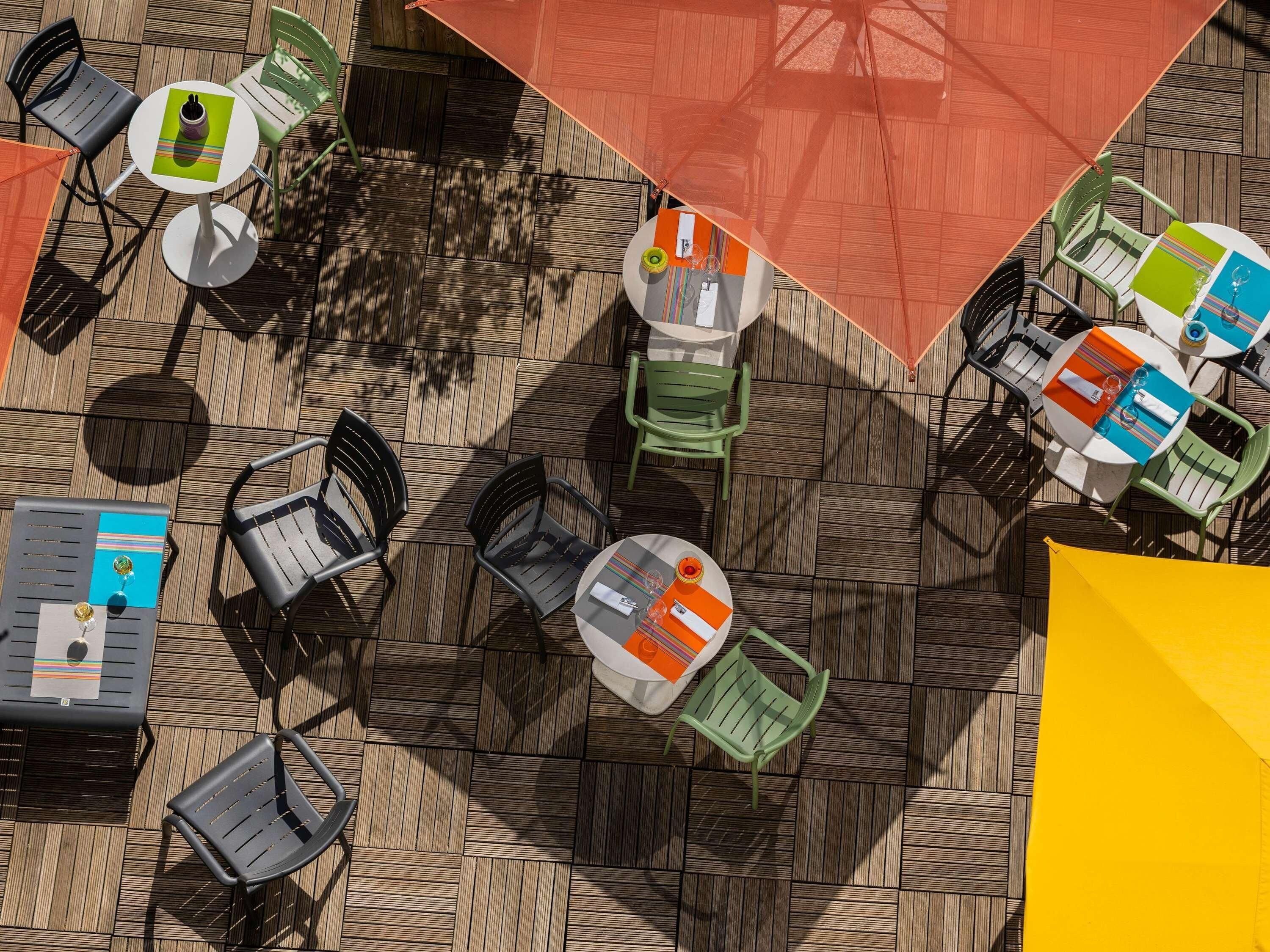 An outdoor seating area with multiple tables and chairs, arranged on a patterned floor.