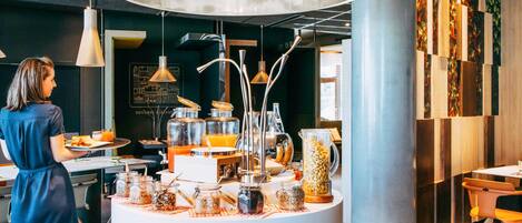 Un bufé de desayuno con diversos alimentos y bebidas, un elemento decorativo central de iluminación y un diseño de interiores moderno.