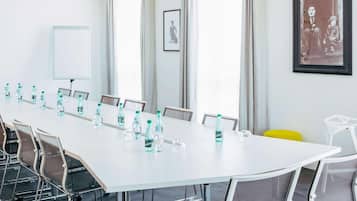 A conference room with a long table, chairs, water bottles, a whiteboard, and framed pictures on the walls.