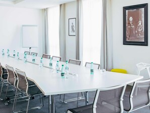 A conference room with a long table, chairs, water bottles, a whiteboard, and framed pictures on the walls. - Novotel Paris Coeur D'orly (Orly)