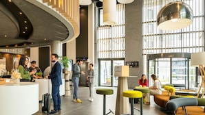 A modern hotel lobby with a curved reception desk, seating areas, and large windows. - Novotel Paris Coeur D'orly (Orly)