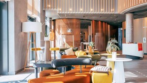 A modern lobby with a sofa, chairs, a reception desk, and a staircase. - Novotel Paris Coeur D'orly (Orly)