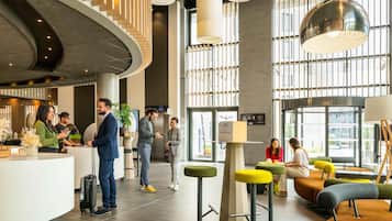 A modern hotel lobby with a curved reception desk, seating areas, and large windows.