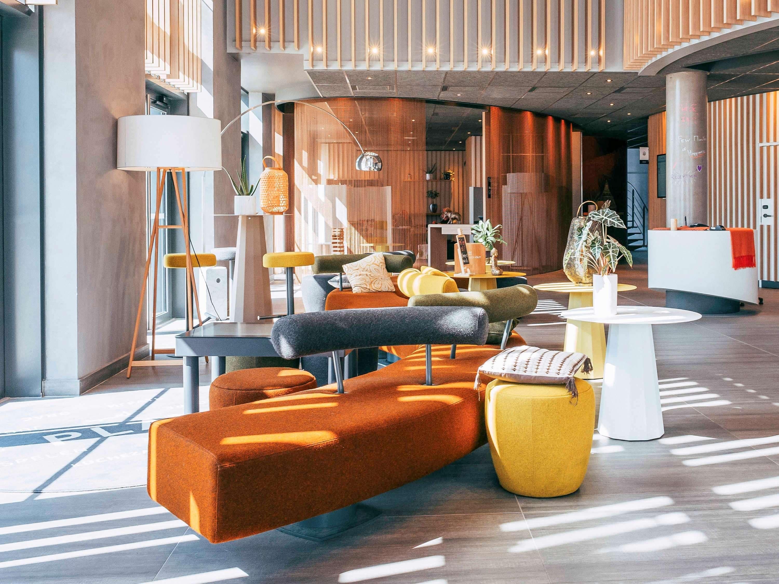 Un vestíbulo moderno con un sofá, sillas, un mostrador de recepción y una escalera.