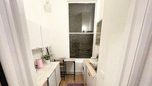 A compact kitchen with a washing machine, a small table, and a purple rug.