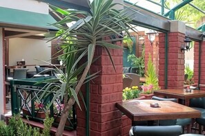 A restaurant with outdoor seating, brick pillars, and potted plants. - Post Boutique Hotel Amman (Amman)