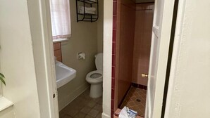 Un baño con inodoro, lavamanos y zona de ducha.