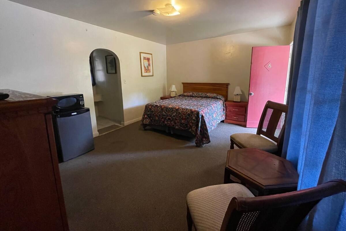 Habitació d'hotel amb un llit, escriptori, cadira, armari i una porta.