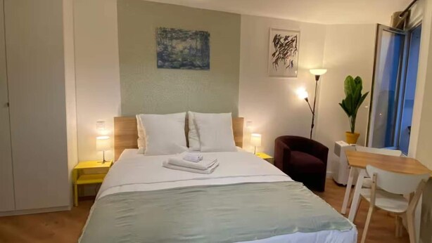 A bedroom with a bed, bedside tables, a desk, a chair, a potted plant, and artwork on the walls. - Studio number 15 in Pantin (Pantin)