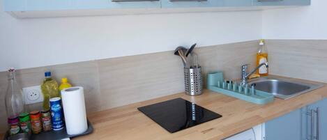A compact kitchen with a washing machine, a sink, and a countertop with various items.