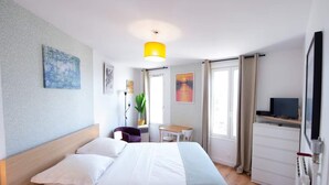 A hotel room with a bed, a desk, a chair, a television, and a window. - Studio number 15 in Pantin (Pantin)