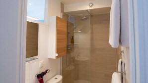 A modern bathroom with a glass-enclosed shower, a white toilet, and a sink. - Studio number 15 in Pantin (Pantin)