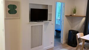Een moderne kamer met een ingebouwde televisie, een radiator, een tafeltje en een stoel.