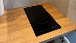 Een moderne keuken met een zwart inductiekookveld en een roestvrijstalen afzuigkap.